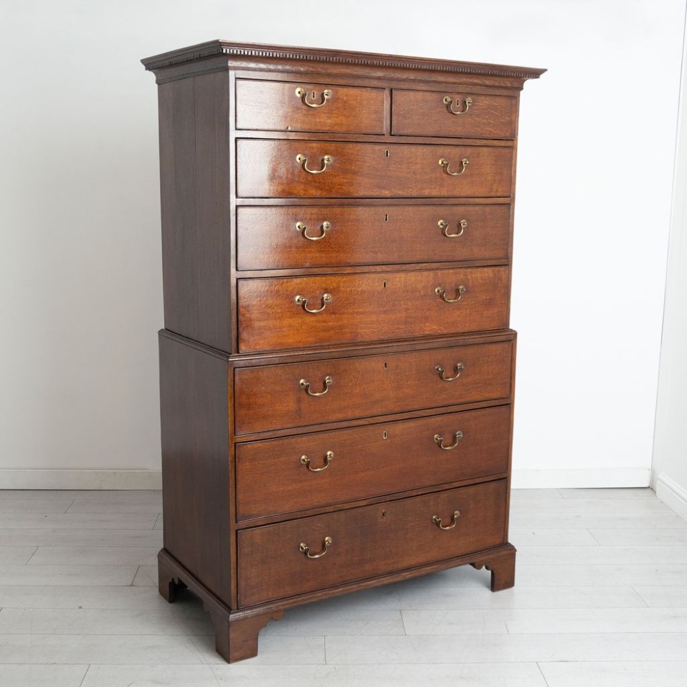 A tall Georgian oak chest on chest featuring two short drawers over five graduated long drawers with brass swan-neck handles and bracket feet. View II