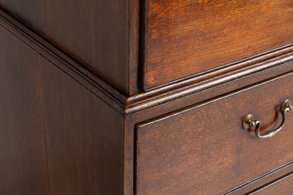 A tall Georgian oak chest on chest featuring two short drawers over five graduated long drawers with brass swan-neck handles and bracket feet. View IV