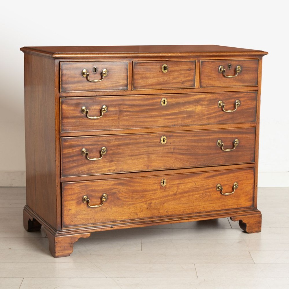 A George III mahogany chest of drawers featuring three small top drawers above three full-width drawers with brass handles and bracket feet. View II