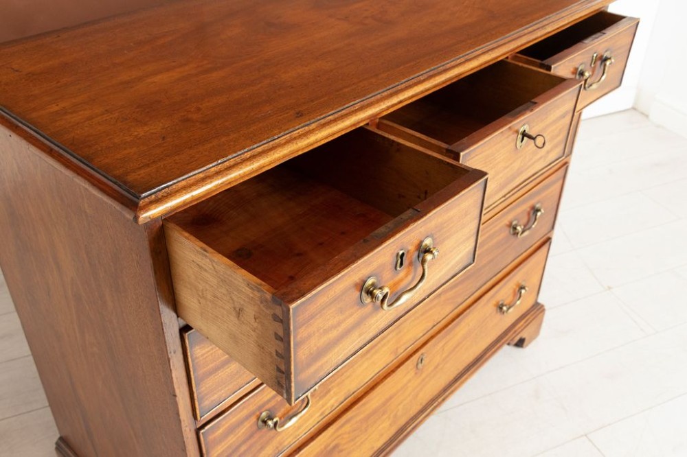 A George III mahogany chest of drawers featuring three small top drawers above three full-width drawers with brass handles and bracket feet. View III