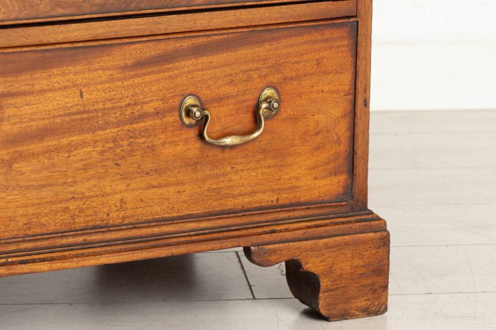 A George III mahogany chest of drawers featuring three small top drawers above three full-width drawers with brass handles and bracket feet. View IV