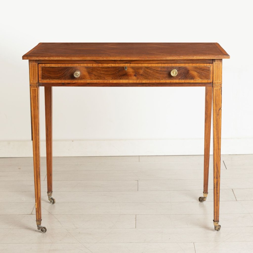 A late nineteenth-century rosewood side table featuring a single drawer with brass knobs, stringing inlay, square tapered legs, and brass castors. View II