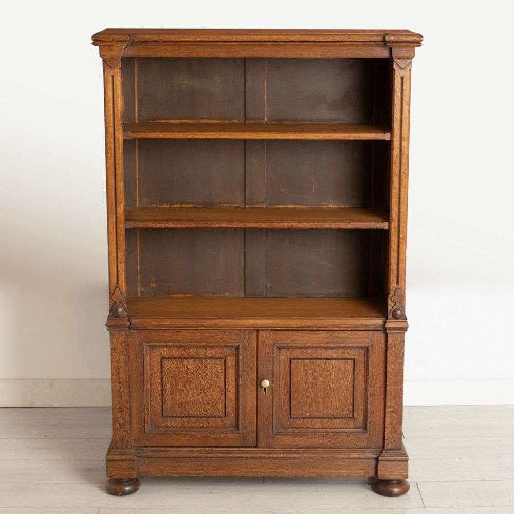 A late 19th-century oak open bookcase featuring two upper shelves above a double-door panelled cupboard base on turned bun feet. View II