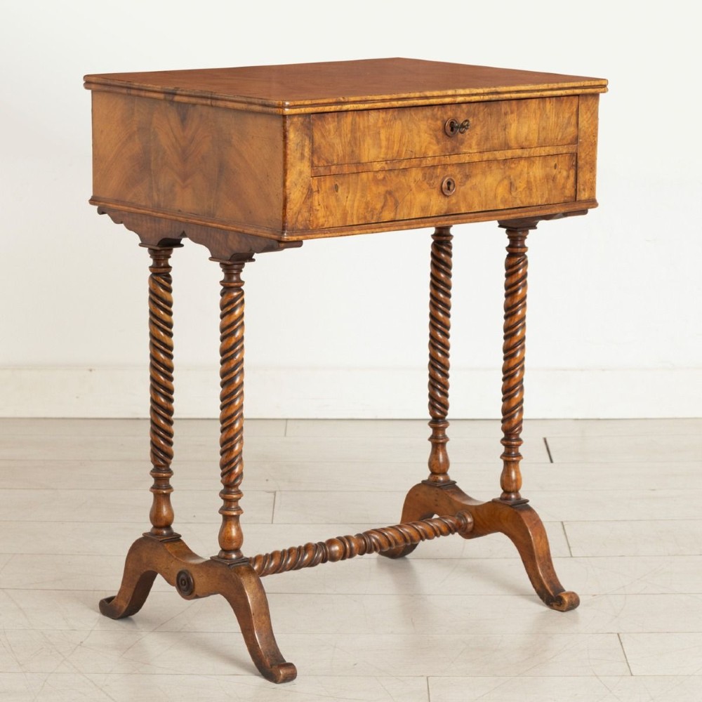 An antique burr walnut sewing table with two drawers, four turned barley twist legs, keyhole details, and a central stretcher base.
