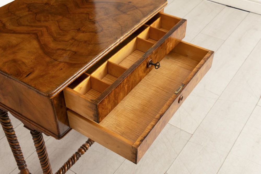 An antique burr walnut sewing table with two drawers, four turned barley twist legs, keyhole details, and a central stretcher base. View III