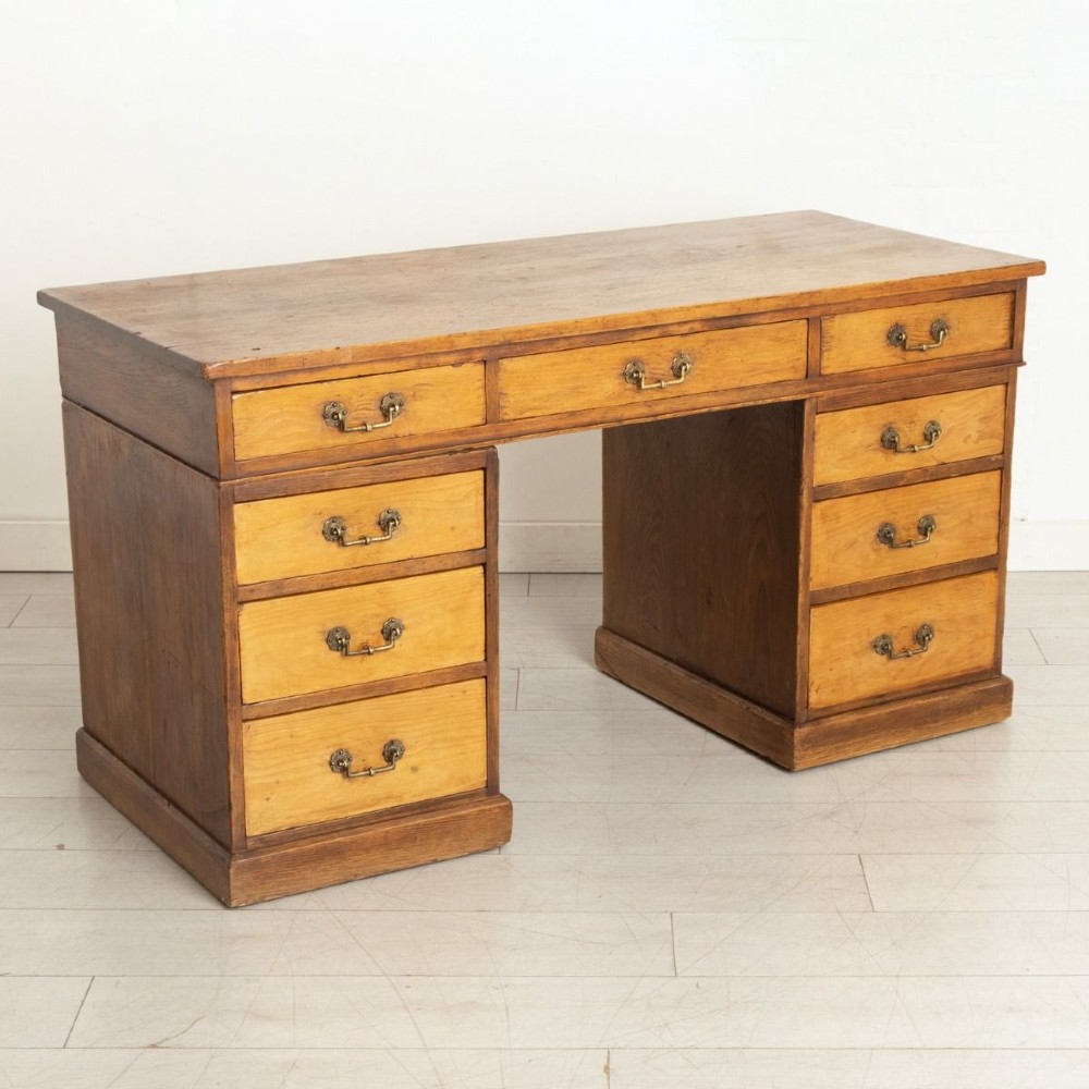 An Edwardian pine pedestal desk featuring nine drawers with brass drop handles and solid plinth bases. View II