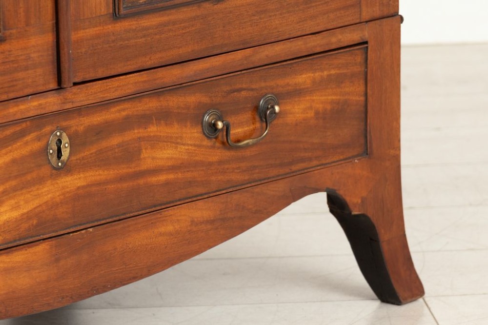A small Georgian mahogany linen press featuring twin panelled doors with flame grain veneers above a single drawer on a shaped apron base. View III