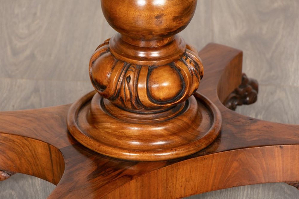 A mid-19th century Victorian burr walnut games table featuring a fold-over rectangular top resting on a turned bulbous pedestal column and a quadripartite base with carved feet on castors. View IV