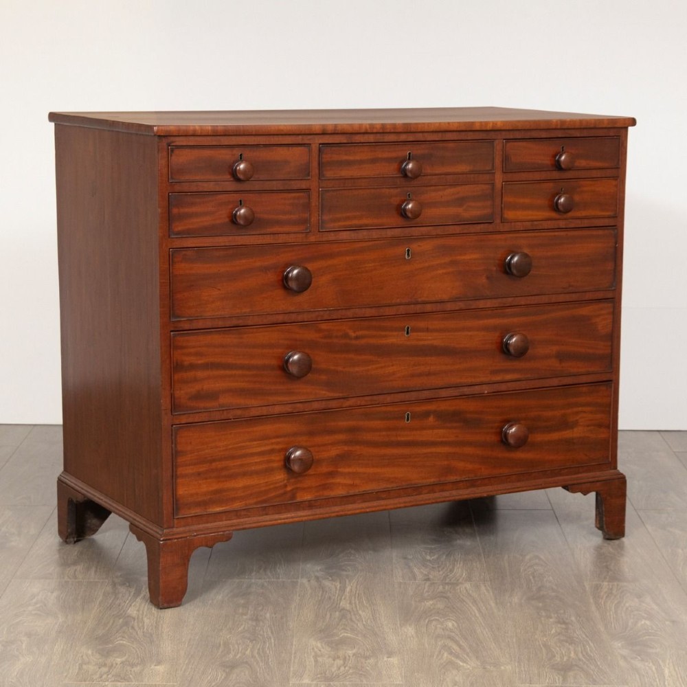 A Georgian mahogany chest of drawers featuring multiple small upper drawers above three full-width lower drawers, supported on shaped bracket feet with turned knob handles.