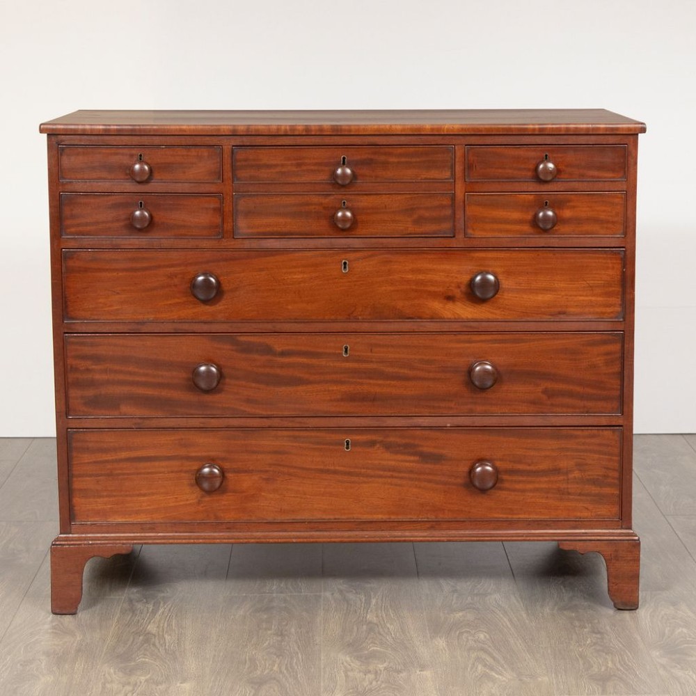 A Georgian mahogany chest of drawers featuring multiple small upper drawers above three full-width lower drawers, supported on shaped bracket feet with turned knob handles. View II