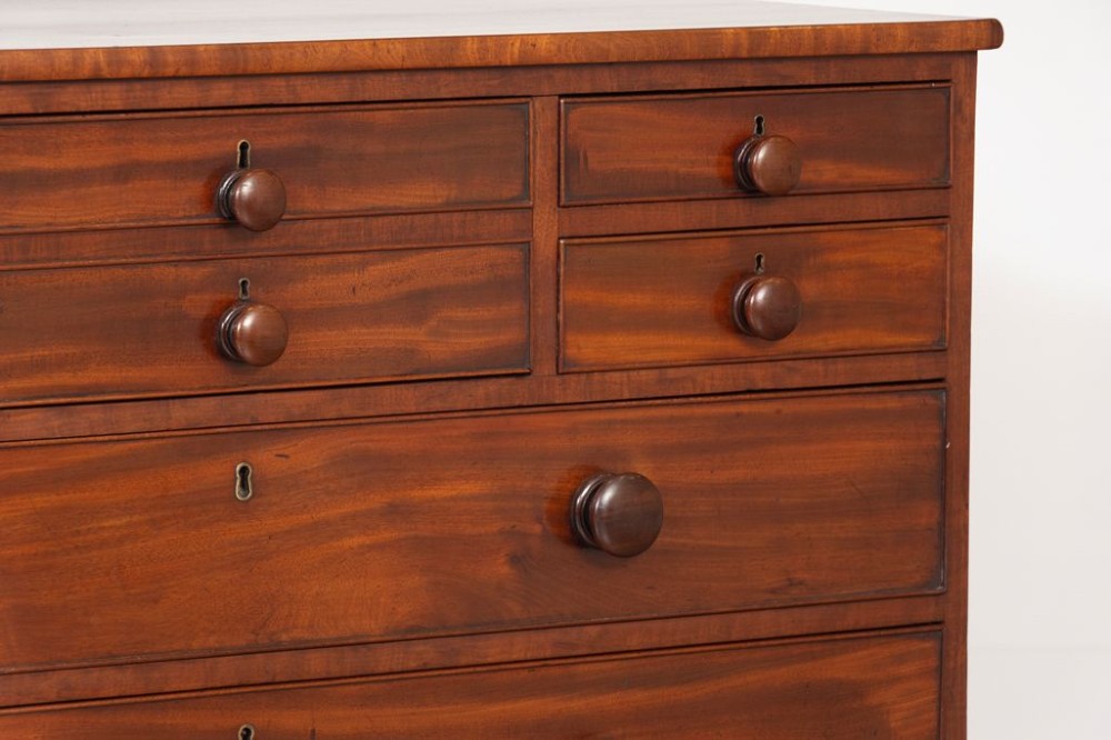 A Georgian mahogany chest of drawers featuring multiple small upper drawers above three full-width lower drawers, supported on shaped bracket feet with turned knob handles. View IV