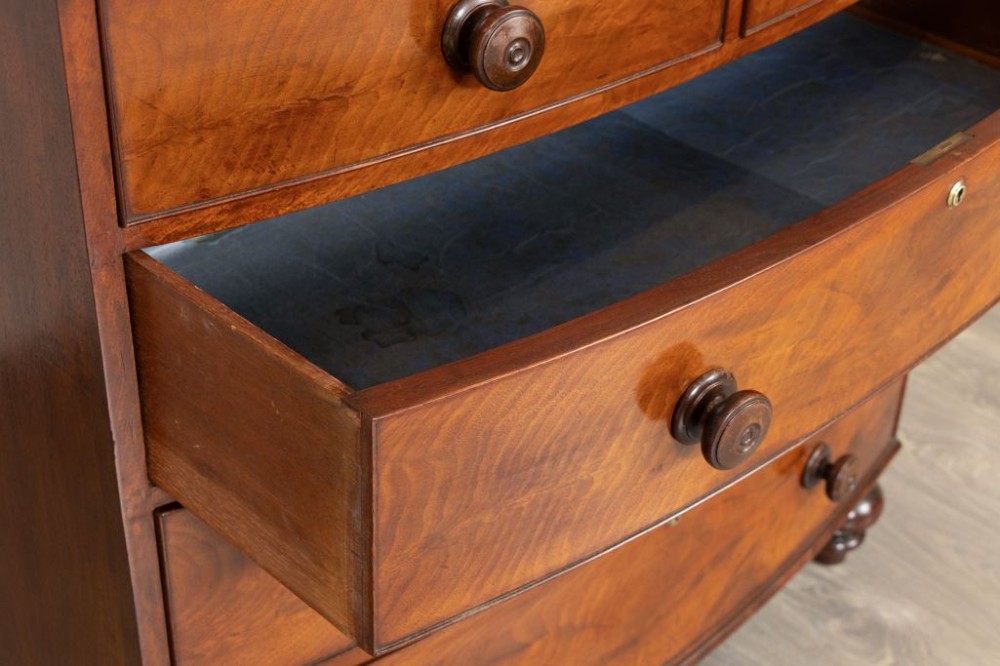 A nineteenth-century Victorian mahogany chest of drawers featuring a bow-front silhouette, four graduated drawers with turned wood knobs, brass keyholes, and turned feet. View III
