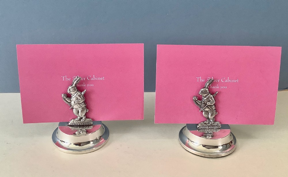 A pair of silver menu holders featuring cast figures of the White Rabbit from Alice in Wonderland, resting on stepped circular bases inside a fitted velvet-lined case. View III