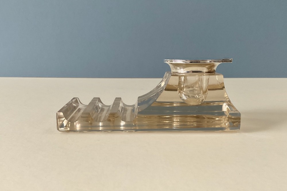 An antique clear glass inkstand featuring a built-in pen tray and an integrated glass inkwell topped with a silver hinged lid. View II