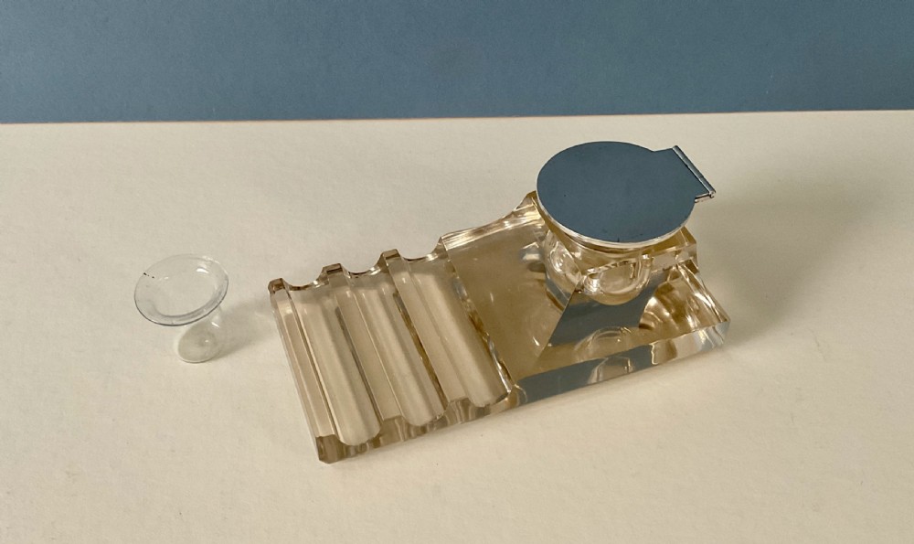 An antique clear glass inkstand featuring a built-in pen tray and an integrated glass inkwell topped with a silver hinged lid. View V