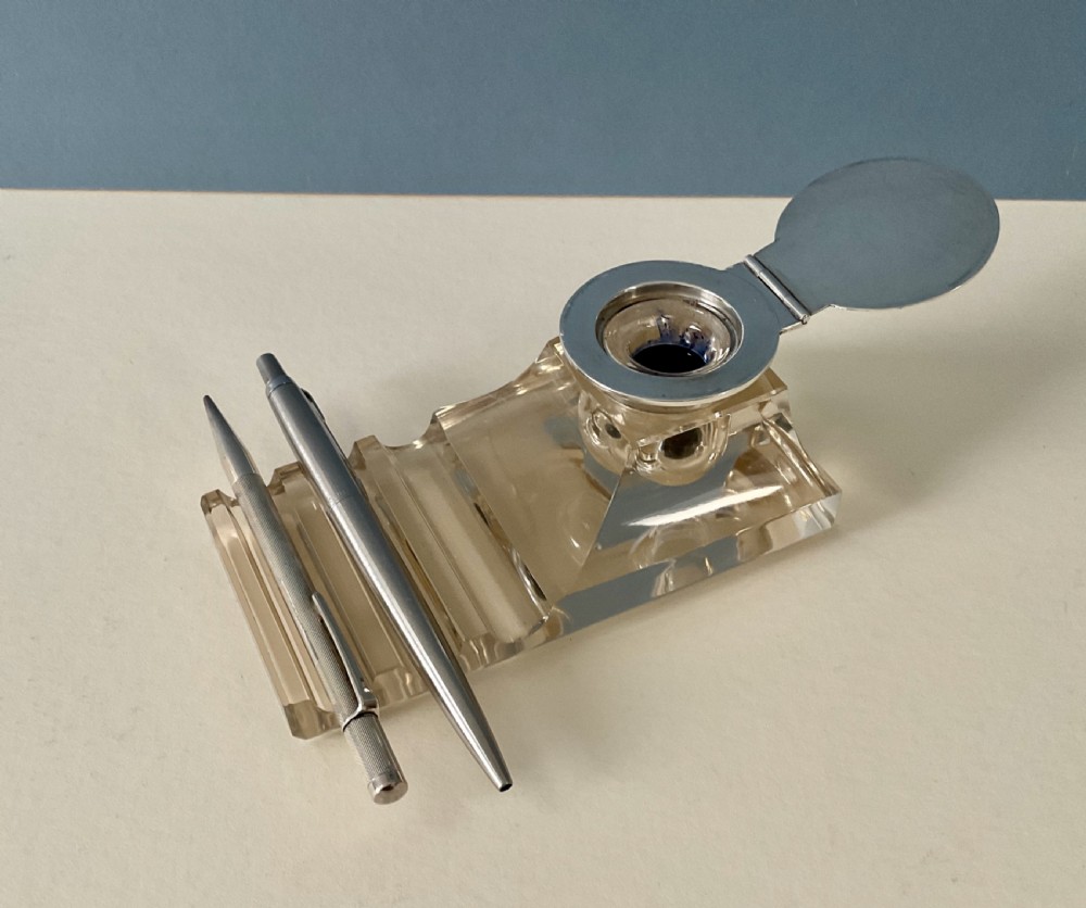 An antique clear glass inkstand featuring a built-in pen tray and an integrated glass inkwell topped with a silver hinged lid. View VIII