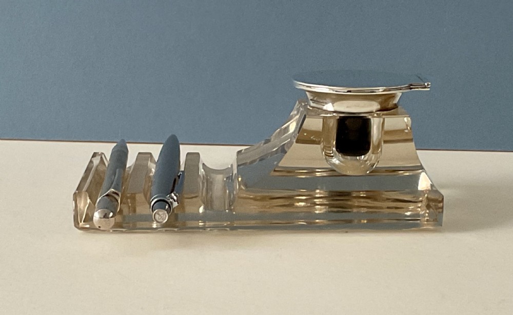 An antique clear glass inkstand featuring a built-in pen tray and an integrated glass inkwell topped with a silver hinged lid. View IX
