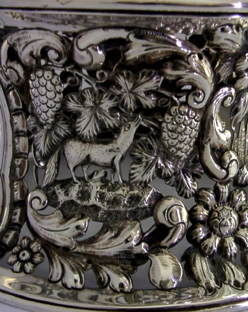 An hourglass-shaped sterling silver dish ring featuring intricately pierced fretwork with floral motifs, scrolls, and marine life details. View V