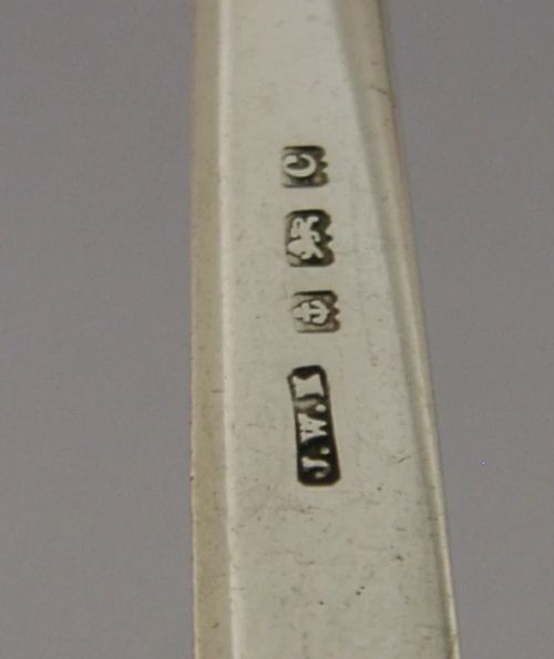 An Edwardian sterling silver letter opener featuring a smooth tapered blade stamped with British hallmarks and a decorative pierced finial housing a red orb. View XI