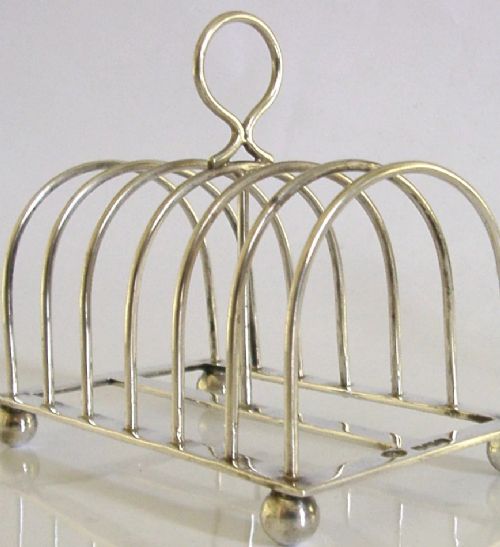 A sterling silver six-slice toast rack featuring seven arched wire divisions, a central loop handle, and four ball feet resting on a rectangular base. View II