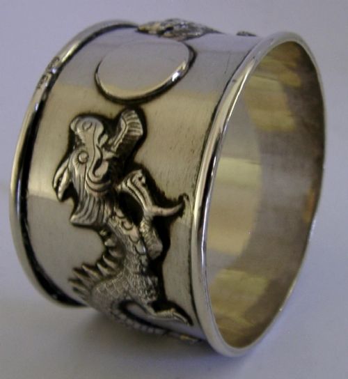A cylindrical silver napkin ring featuring a relief-carved Chinese dragon motif against a polished surface. View VI