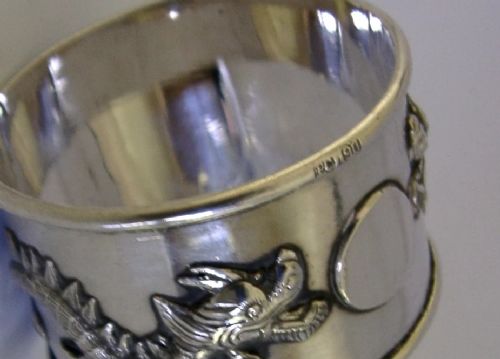 A cylindrical silver napkin ring featuring a relief-carved Chinese dragon motif against a polished surface. View VII