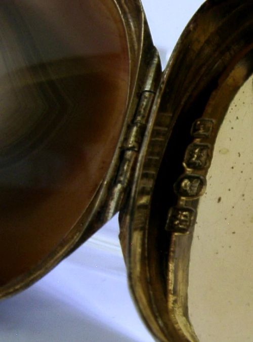 An open Georgian silver oval vinaigrette box featuring a translucent banded agate lid insert and a perforated gold-gilded floral inner grille. View XII
