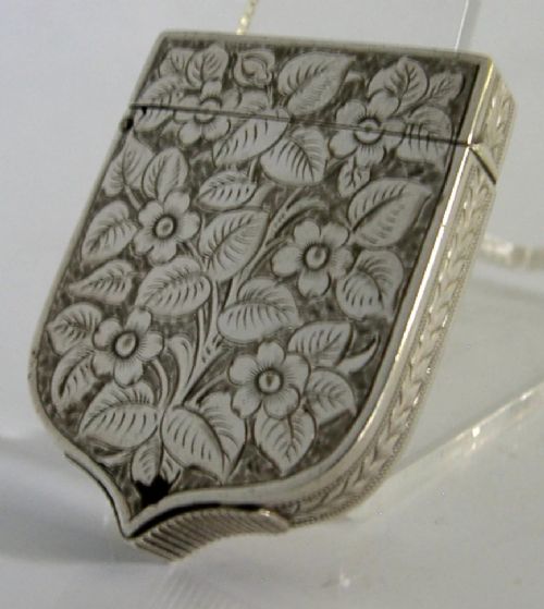 A Victorian shield-shaped sterling silver vesta case engraved with floral motifs and a central vacant cartouche. View II
