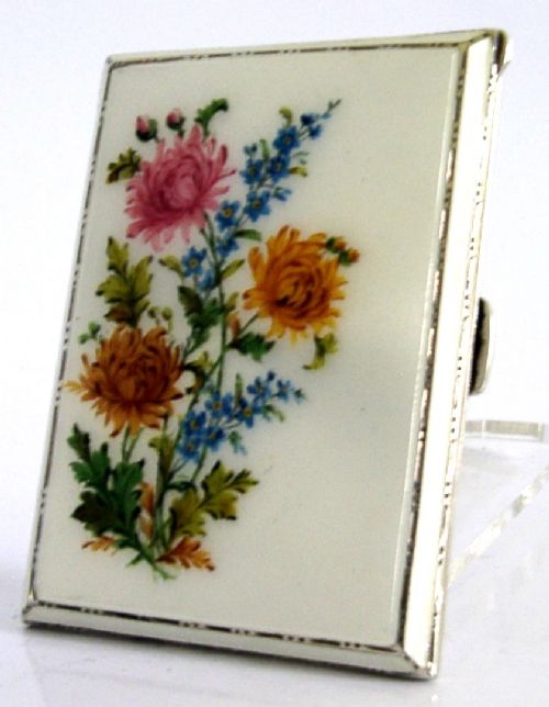A square sterling silver hinged cigarette case showing an engine-turned textured exterior on one side and a white enamelled panel with hand-painted yellow and pink chrysanthemums on the other. View IV