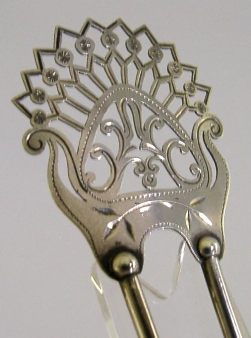 An antique sterling silver two-prong hair slide featuring a fan-shaped pierced crest with scrolling motifs and geometric openwork. View III