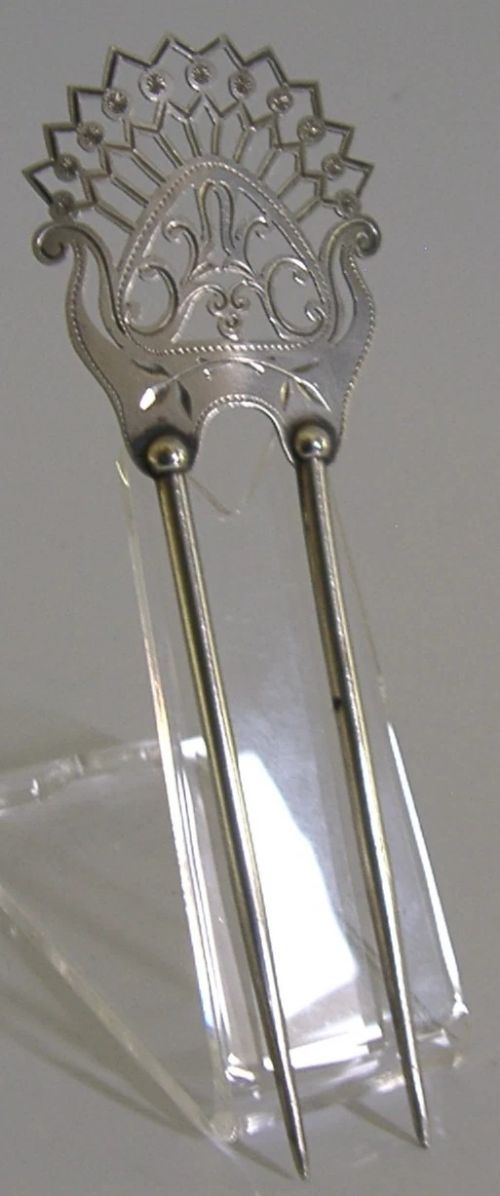An antique sterling silver two-prong hair slide featuring a fan-shaped pierced crest with scrolling motifs and geometric openwork. View IV