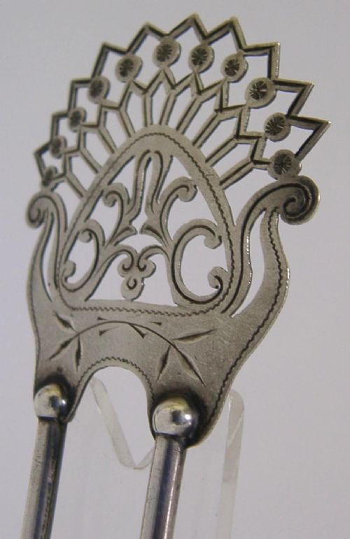 An antique sterling silver two-prong hair slide featuring a fan-shaped pierced crest with scrolling motifs and geometric openwork. View VI
