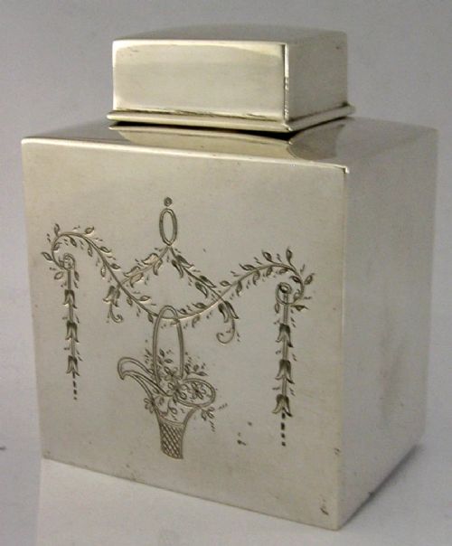 An antique Edwardian rectangular sterling silver tea caddy decorated with delicate engraved floral swags and a central flower basket, topped with a square cap lid. View II