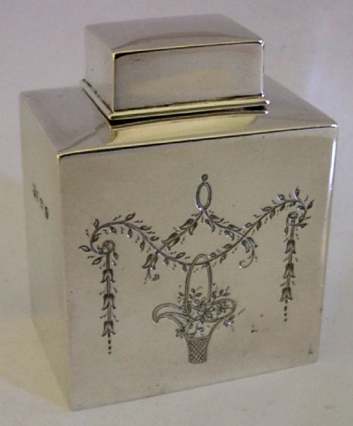 An antique Edwardian rectangular sterling silver tea caddy decorated with delicate engraved floral swags and a central flower basket, topped with a square cap lid. View VI
