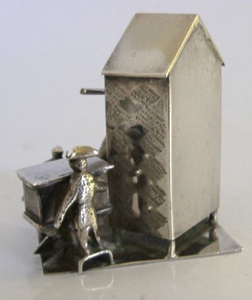An 833 solid silver miniature model depicting a Punch and Judy puppet show booth with figures, an organ grinder, and a dog on a flat silver base. View IV