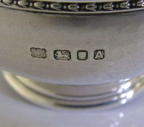 A planished sterling silver bowl featuring a hand-hammered finish, patterned rim, pedestal base, and British hallmarks stamped on the side. View IX