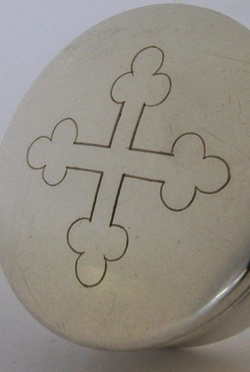 A small circular sterling silver pyx box featuring an engraved cross on the cover and a gold gilt interior. View II