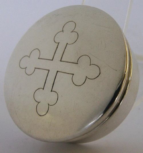 A small circular sterling silver pyx box featuring an engraved cross on the cover and a gold gilt interior. View IV