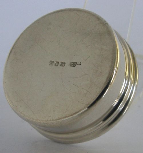 A small circular sterling silver pyx box featuring an engraved cross on the cover and a gold gilt interior. View VII