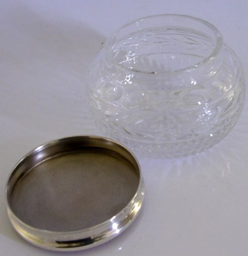 A circular cut glass vanity jar with a sterling silver rim and a bronze guilloche enamelled lid displaying a sunburst pattern. View V