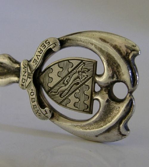 An Art Deco sterling silver spoon featuring an openwork coat of arms handle terminal, a geometric stem, and a polished teardrop bowl. View IV
