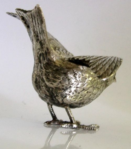 A solid silver pepper pot finely chased in the detailed form of a bird chick with outstretched wings. View VI