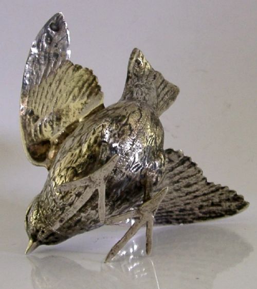 A solid silver pepper pot finely chased in the detailed form of a bird chick with outstretched wings. View VIII