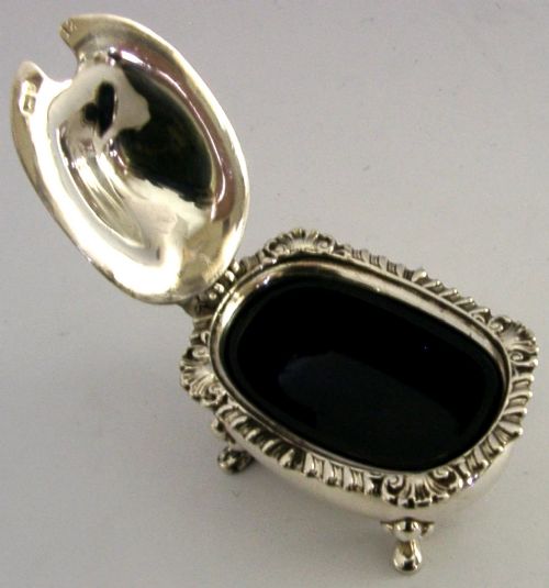 A solid sterling silver mustard pot featuring a domed hinged lid with a finial, decorative scalloped rim, scroll handle, and four pad feet. View V