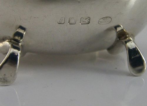 A solid sterling silver mustard pot featuring a domed hinged lid with a finial, decorative scalloped rim, scroll handle, and four pad feet. View VII