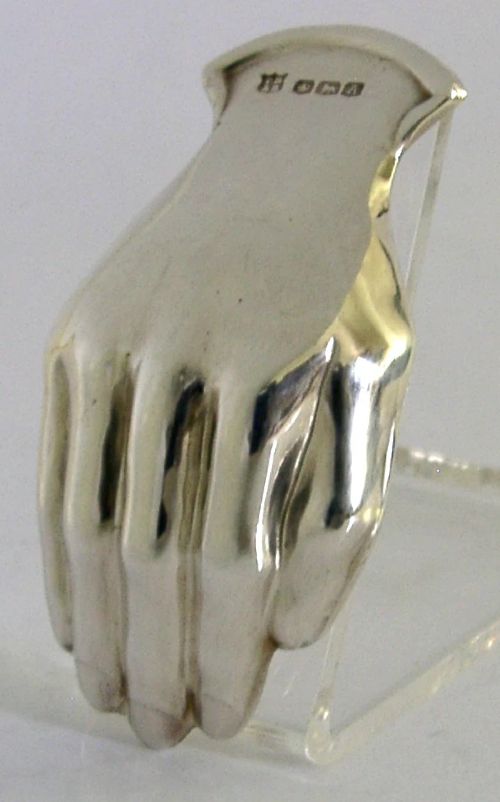 A sterling silver tea caddy spoon shaped like an open human hand with visible hallmarks stamped near the wrist handle. View V