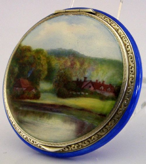 An open Art Deco sterling silver powder compact featuring a cobalt blue enamel rim and a hand-painted landscape scene on the lid interior. View V