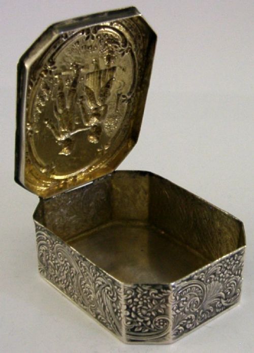 An octagonal antique silver table box featuring a detailed repousse scene of a couple in 18th-century attire within a scrollwork frame. View VI