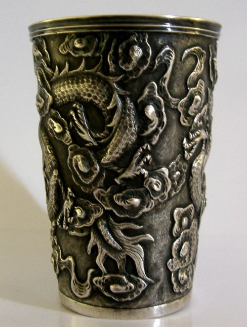A cylindrical Chinese export silver beaker featuring high-relief repousse dragon motifs and an oval cartouche engraved with a royal monogram beneath a crown. View IV