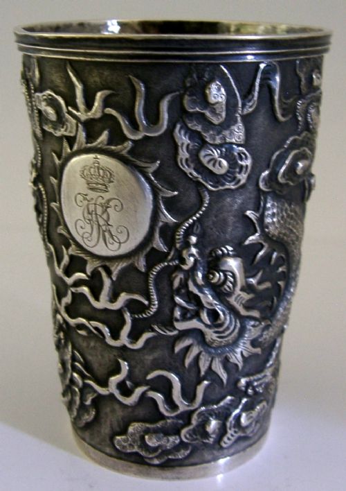 A cylindrical Chinese export silver beaker featuring high-relief repousse dragon motifs and an oval cartouche engraved with a royal monogram beneath a crown. View V